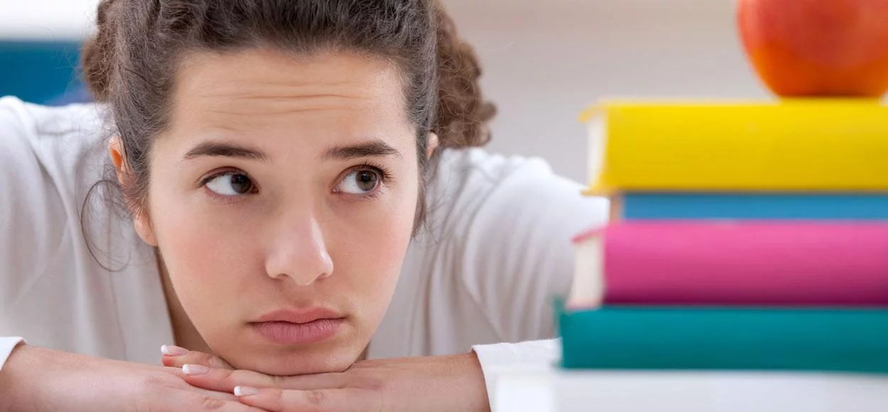 meisje kijkt naar een stapel boeken