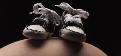 babyschoentjes op een zwangere buik